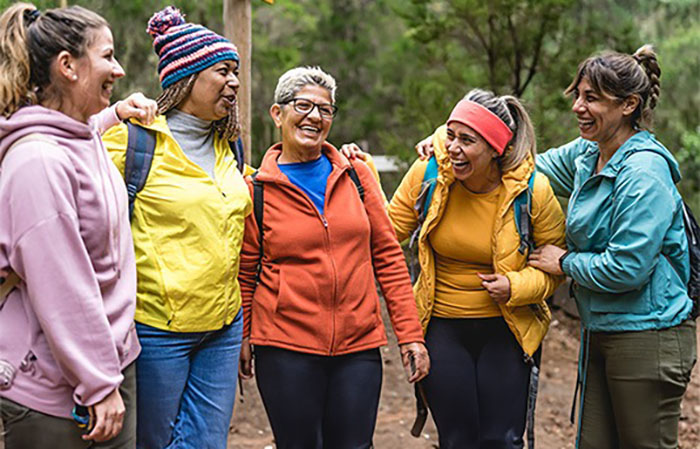 a group of women laugh while on a hiking trip.
